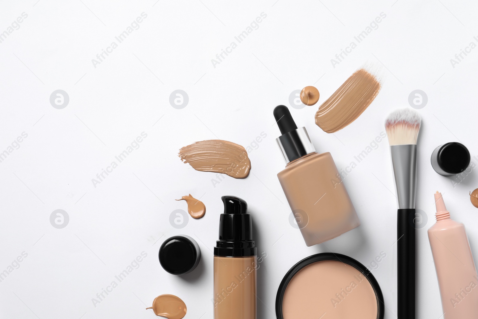 Photo of Liquid foundations, makeup brush, swatches and face powder on white background, flat lay. Space for text