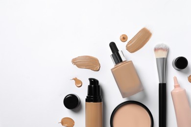 Liquid foundations, makeup brush, swatches and face powder on white background, flat lay. Space for text