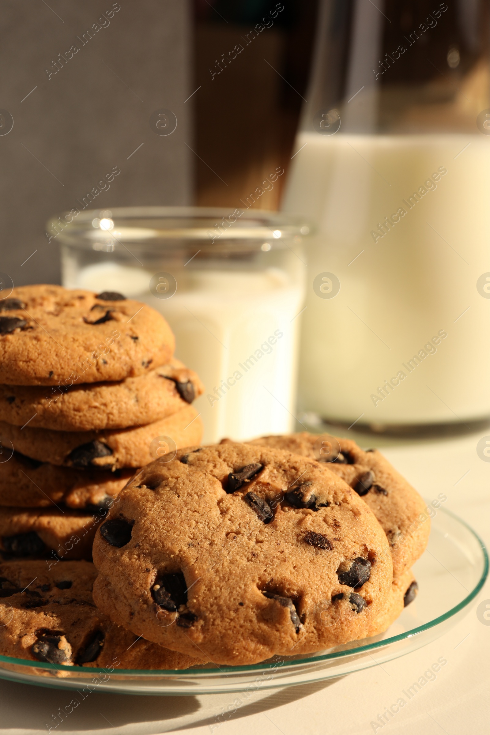 Photo of Delicious chocolate chip cookies and milk on white marble table