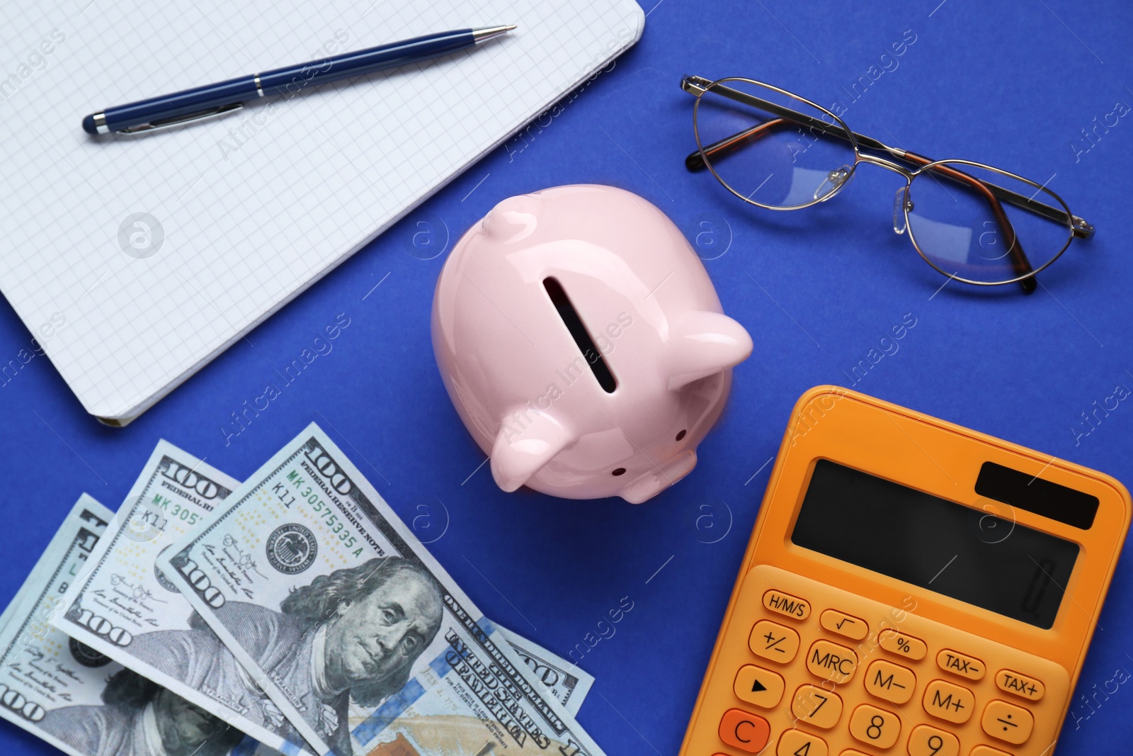 Photo of Flat lay composition with piggy bank, glasses and banknotes on blue background