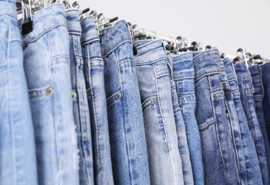 Photo of Rack with different jeans on light background, closeup