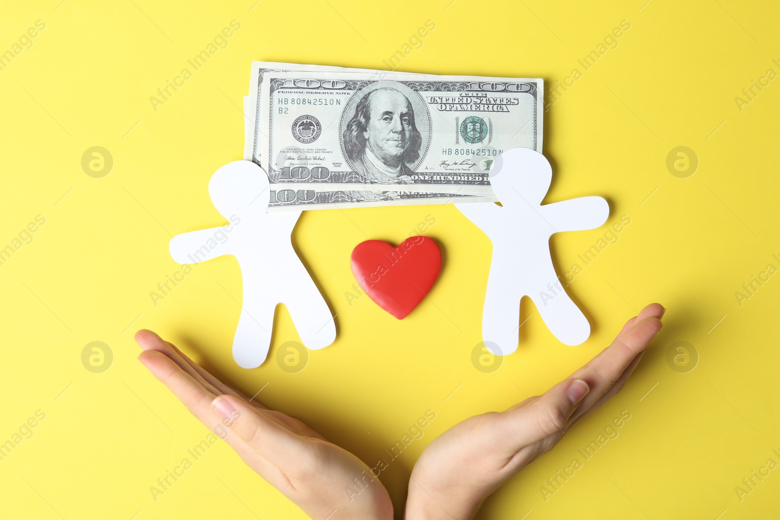 Photo of Woman holding hands near paper silhouettes of people, heart and money bills on color background, top view. Life insurance concept