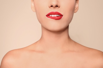 Beautiful young woman with red lips on color background, closeup