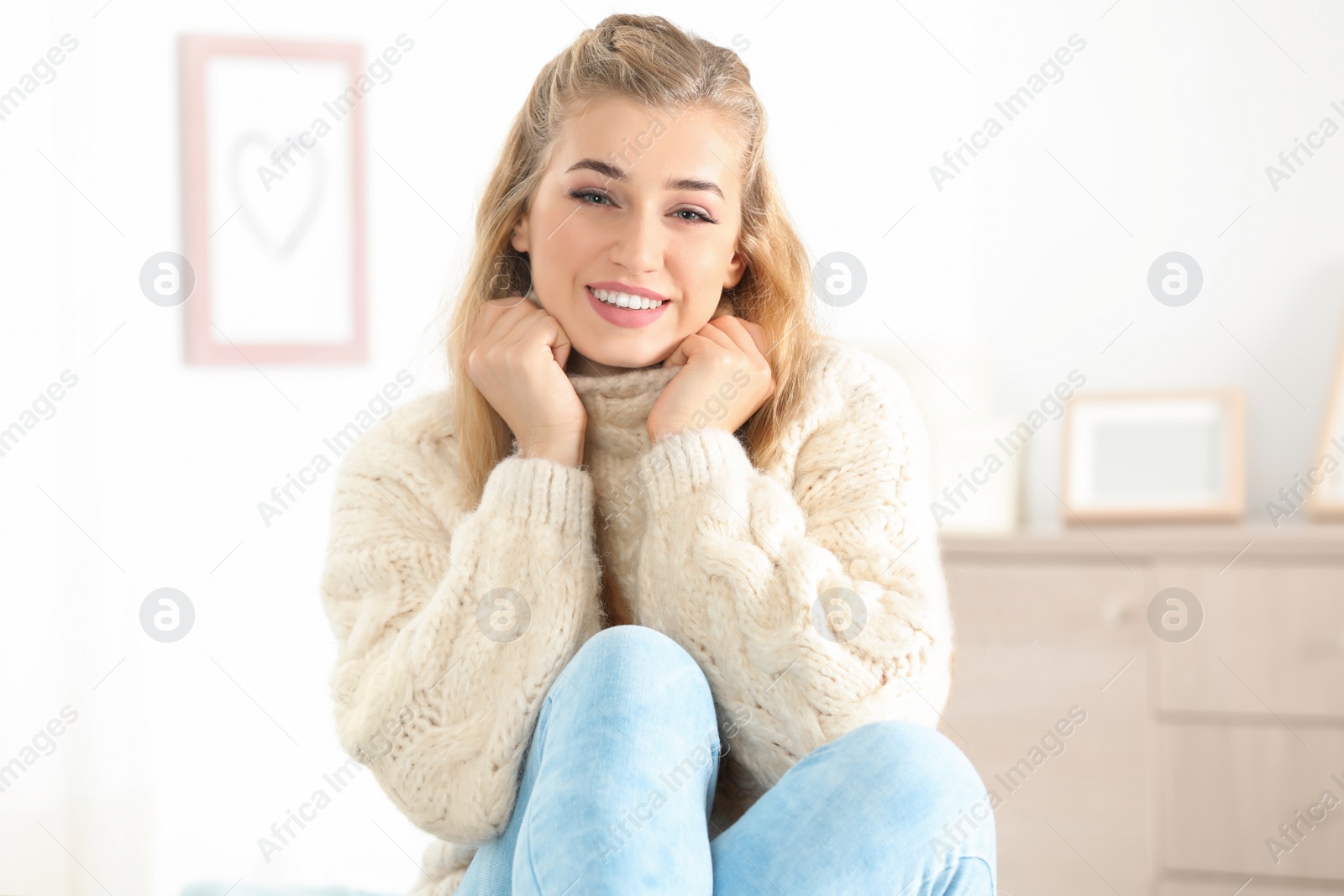 Photo of Beautiful smiling young woman in cozy warm sweater at home