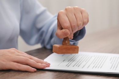 Woman stamping document at wooden table, closeup