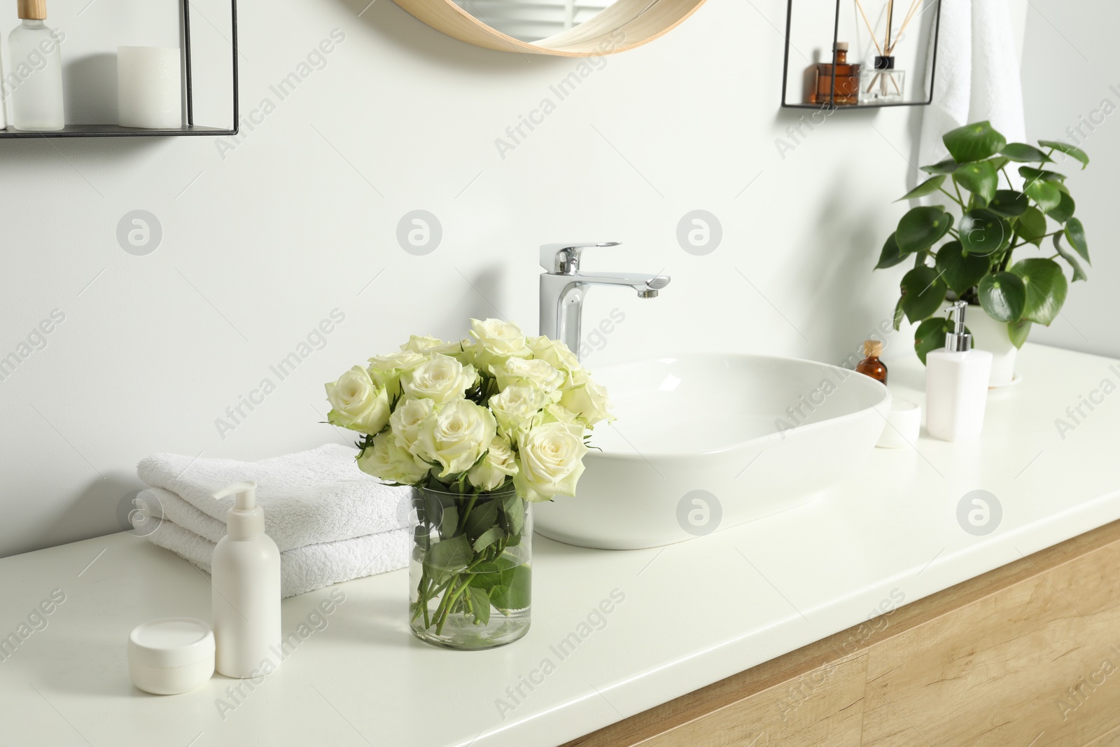 Photo of Beautiful roses and bath accessories near sink in bathroom