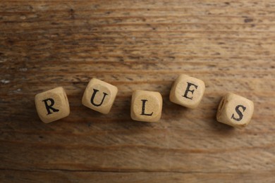 Photo of Word Rules made of cubes with letters on wooden table, top view
