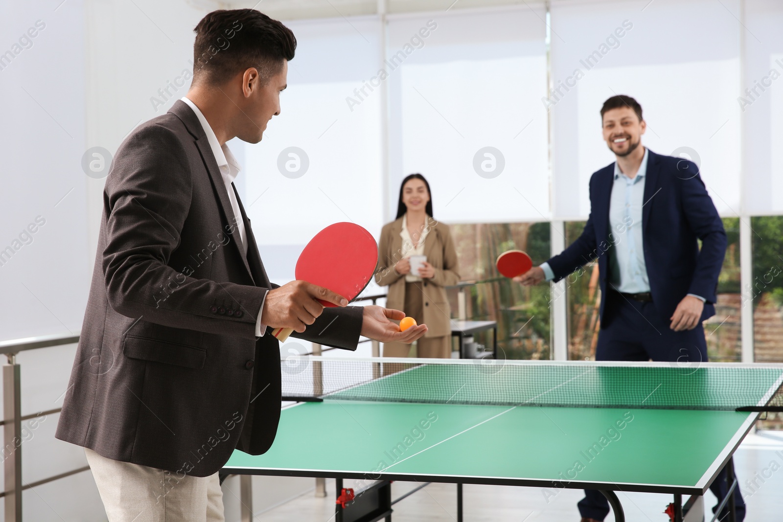 Photo of Business people playing ping pong in office