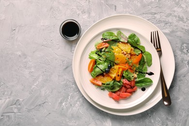 Photo of Delicious salad with salmon served on gray textured table, flat lay. Space for text