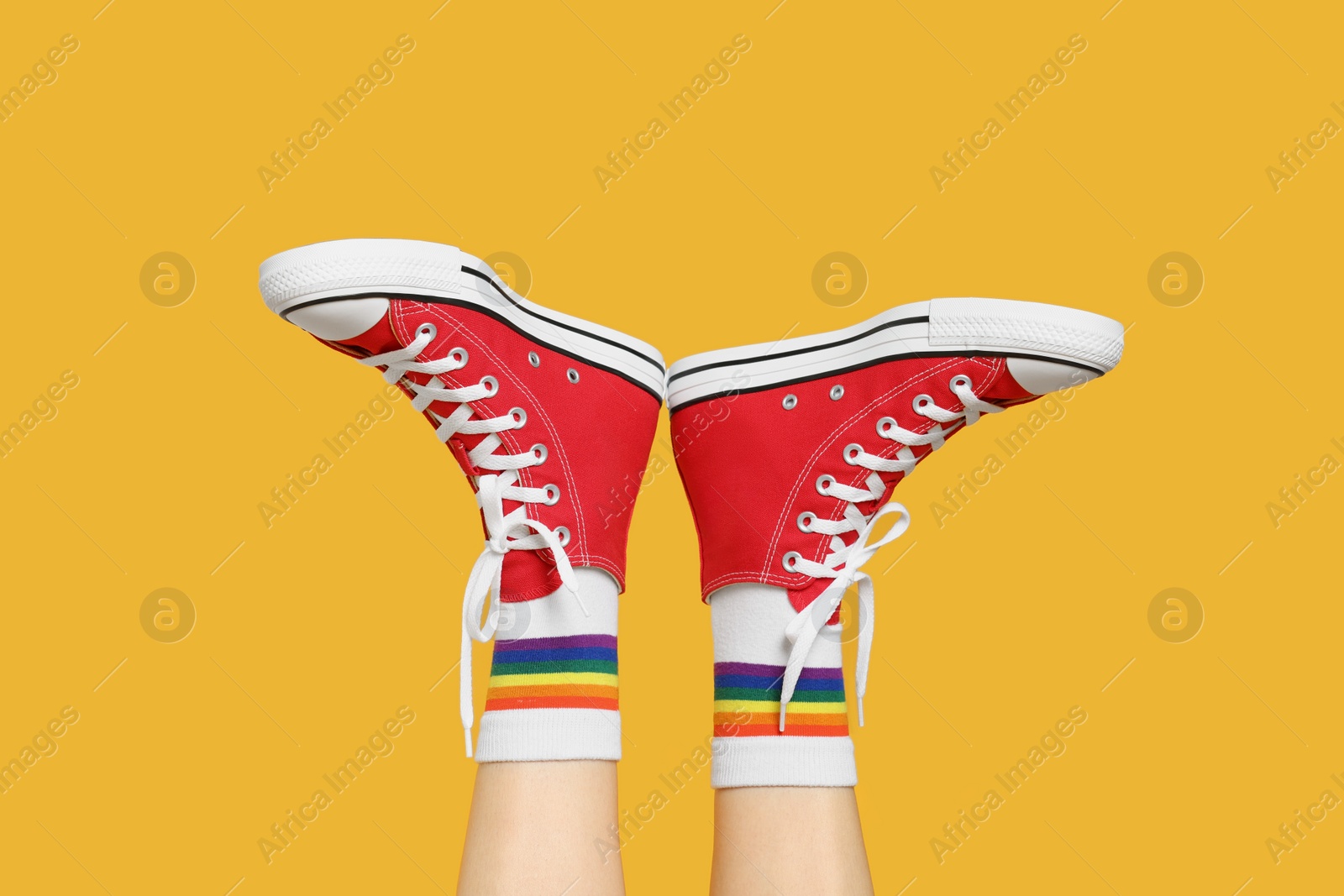 Photo of Woman in stylish gumshoes on yellow background, closeup