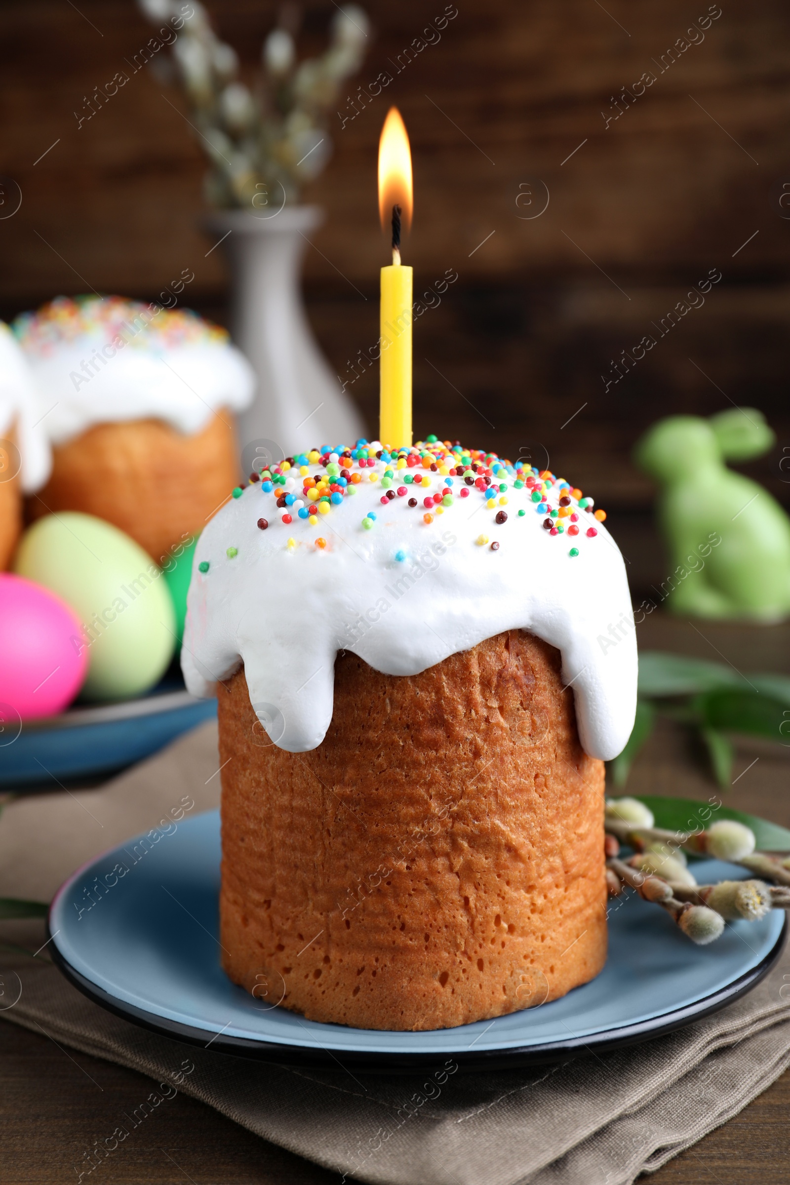 Photo of Easter cake with burning candle on wooden table