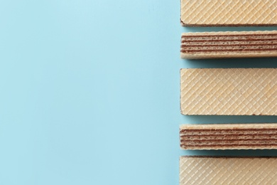 Photo of Tasty wafer sticks on blue background, flat lay with space for text. Sweet food