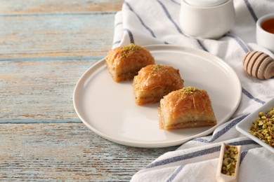 Photo of Delicious sweet baklava with pistachios on light blue wooden table, space for text