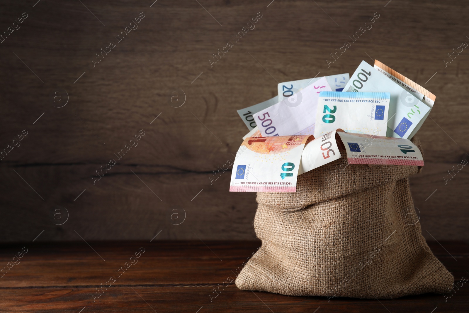 Image of Sack full of money on wooden table. Space for text 