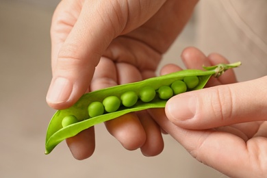 Photo of Young woman shelling fresh green peas, closeup