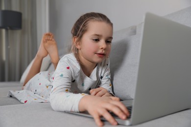 Photo of Little girl learning English indoors at online lesson