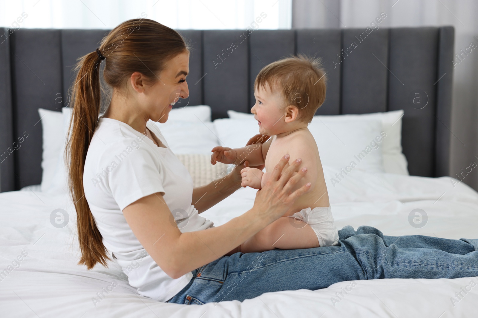 Photo of Happy mother with her baby on bed at home