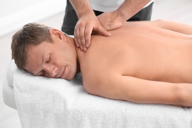 Photo of Relaxed man receiving back massage in wellness center