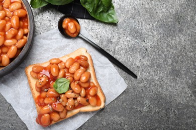 Photo of Toast with delicious canned beans on grey table, flat lay. Space for text
