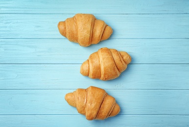 Tasty croissants on wooden background, top view