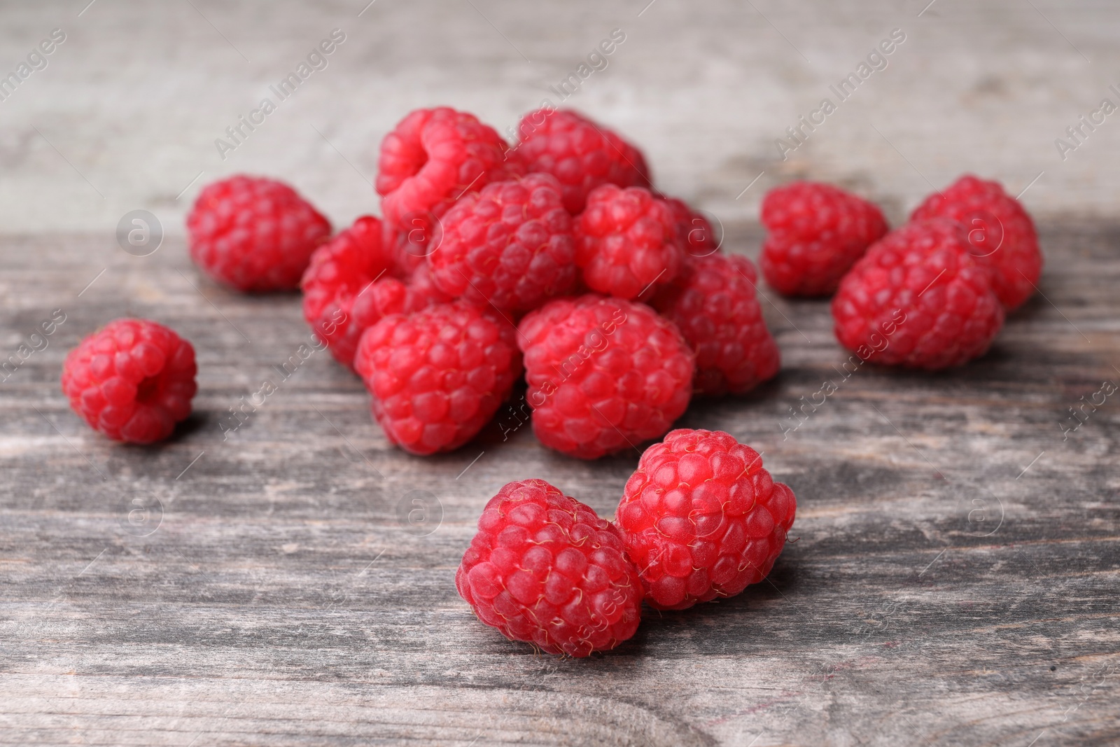 Photo of Heap of tasty ripe raspberries on wooden table, closeup