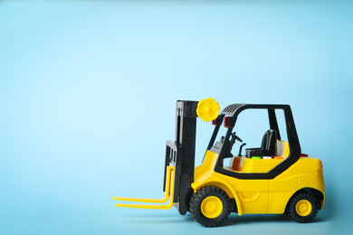 Photo of Toy forklift on blue background, space for text. Logistics and wholesale concept