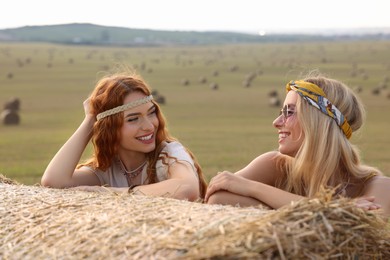 Photo of Beautiful hippie women near hay bale in field
