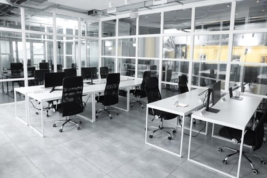 Photo of Stylish interior of open plan office. Workspace with computers, tables and chairs