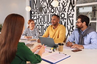 Photo of Team of employees working together at table in office. Startup project