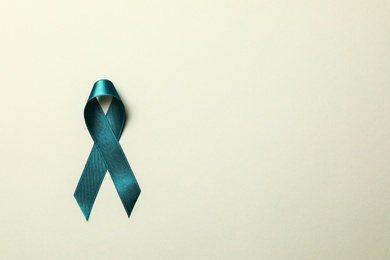 Photo of Teal awareness ribbon on light background, top view with space for text. Symbol of social and medical issues