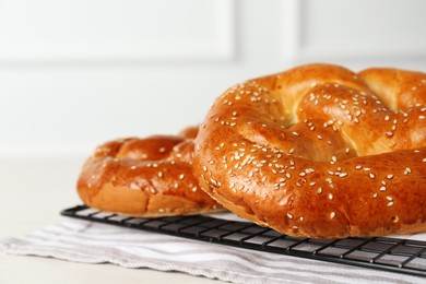 Photo of Tasty freshly baked pretzels on cooling grid, closeup view