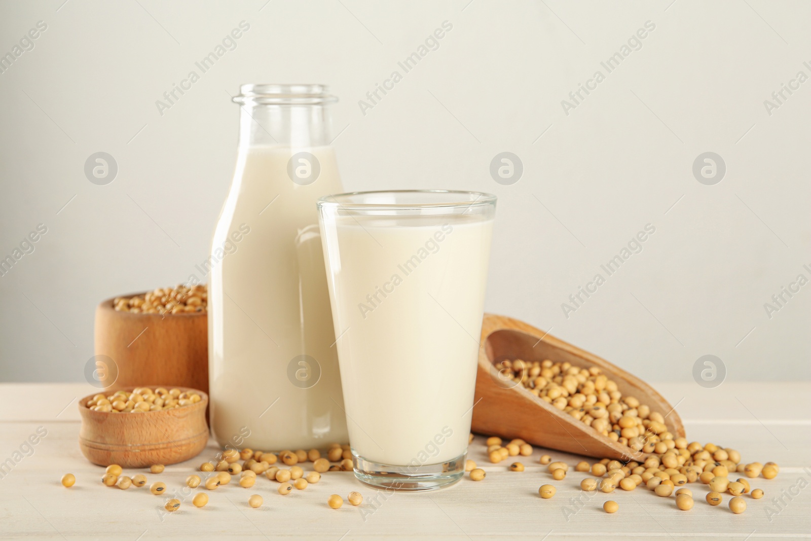 Photo of Fresh soy milk and grains on white wooden table