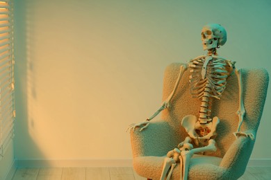 Photo of Waiting concept. Human skeleton sitting in armchair indoors, space for text