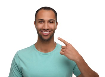 Photo of Smiling man pointing at his healthy clean teeth on white background