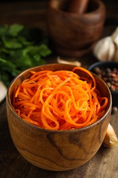 Photo of Delicious Korean carrot salad in bowl on wooden board