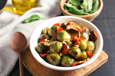 Photo of Bowl of warm salad with Brussels sprouts and carrots on table