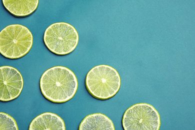 Photo of Juicy fresh lime slices on blue background, flat lay. Space for text