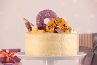 Photo of Delicious cake decorated with sweets and gift boxes on light background