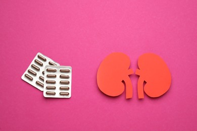 Photo of Paper cutout of kidneys and pills on magenta background, flat lay