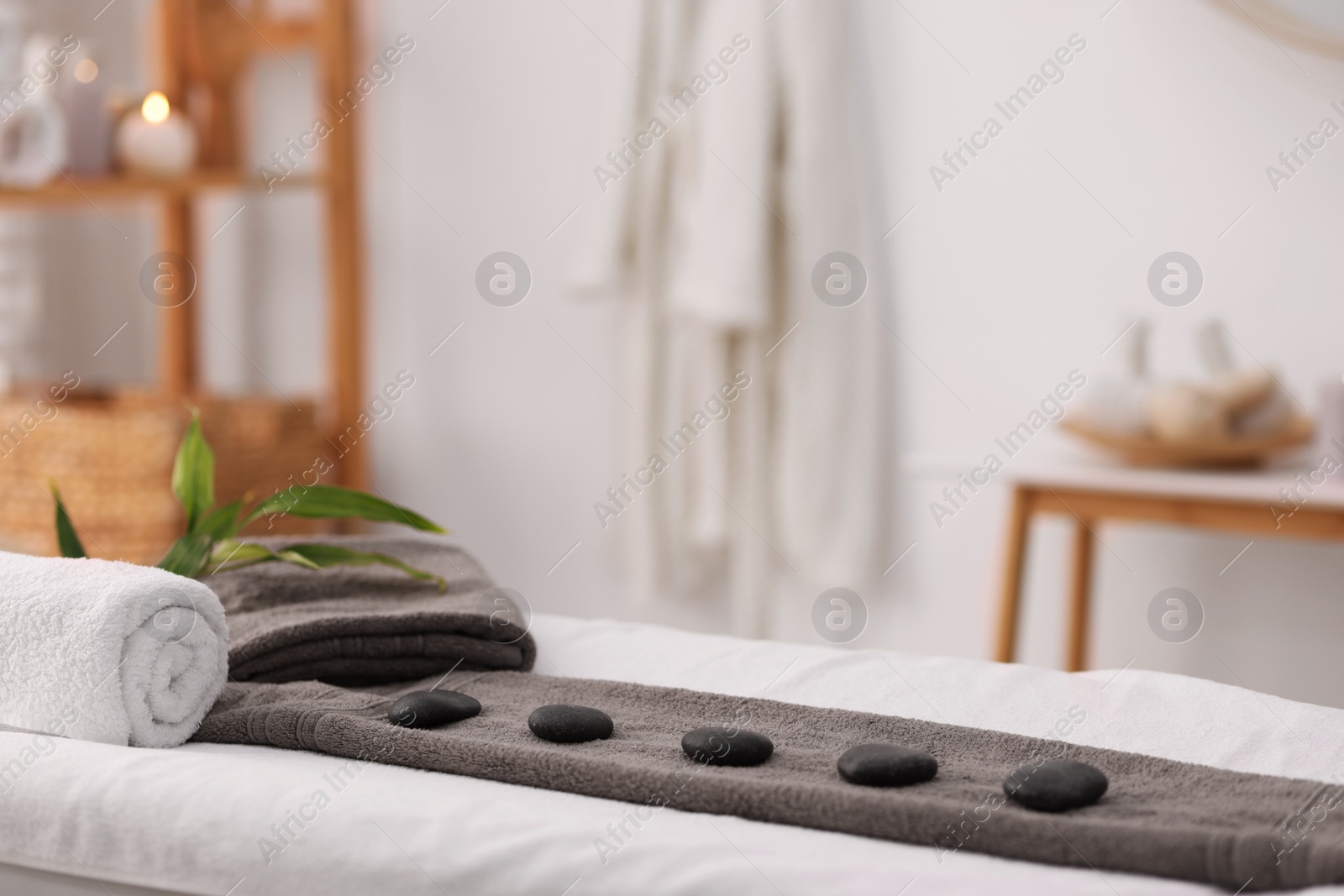 Photo of Towel with arranged spa stones on massage table in recreational center