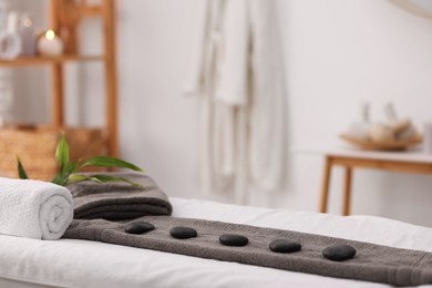 Photo of Towel with arranged spa stones on massage table in recreational center