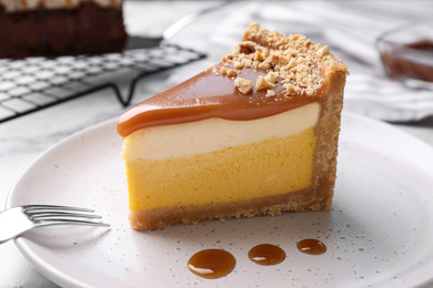 Photo of Piece of delicious cake with caramel on plate, closeup