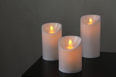 Photo of Glowing decorative LED candles on black table