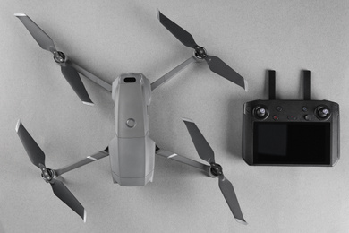 Photo of Modern drone with controller on grey background, top view