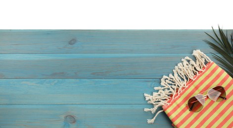 Photo of Light blue wooden surface with beach towel and sunglasses on white background, top view. Space for text