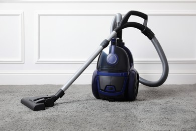 Photo of Modern vacuum cleaner near white wall indoors