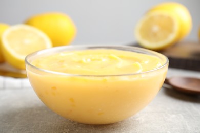 Photo of Delicious lemon curd in bowl on grey table, closeup