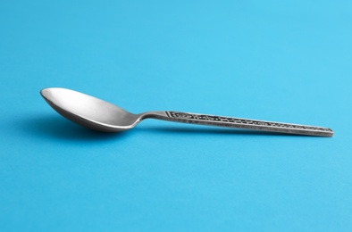 Photo of Clean empty vintage tea spoon on blue background