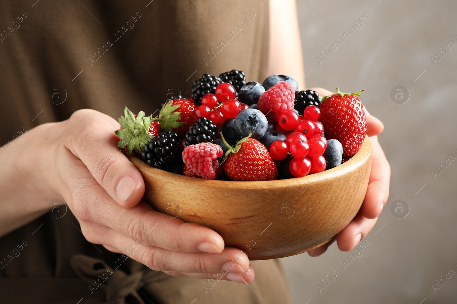 Photo of Woman with bowl of delicious summer berries, closeup