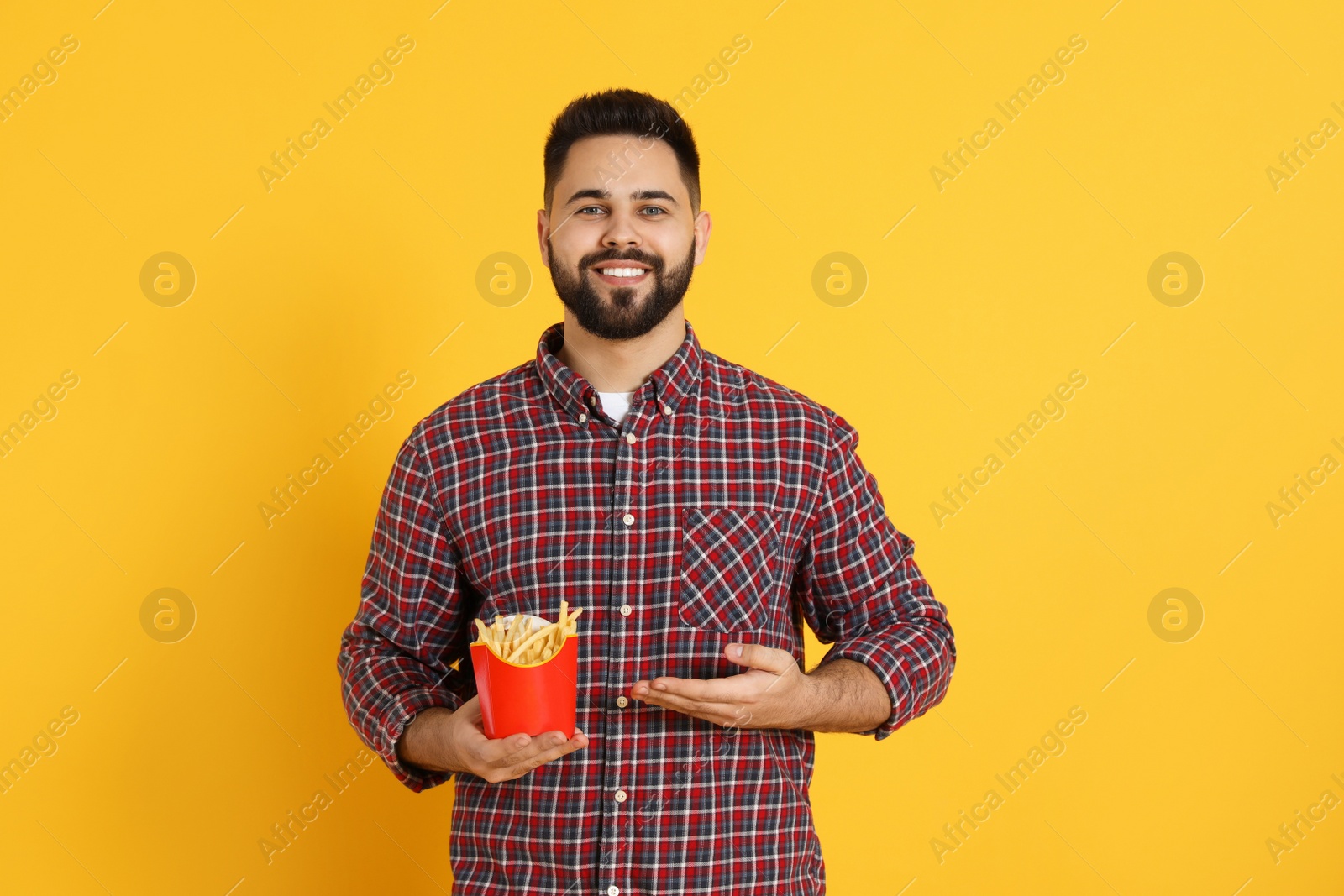 Photo of Young man with French fries on orange background
